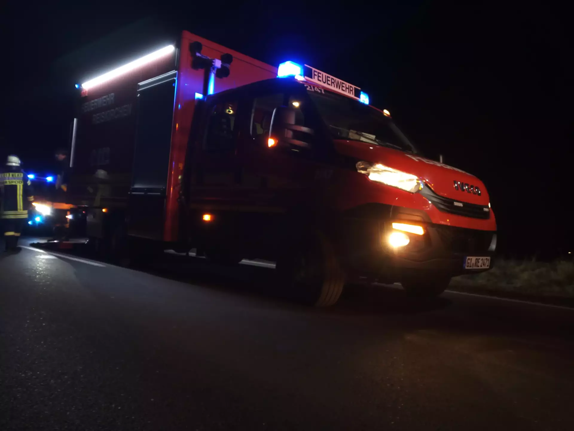 Tragkraftspritzenfahrzeug Logistik im Einsatz mit Feuerwehrleuten im Hintergrund